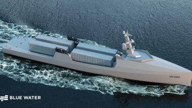 Rendering of an autonomous ship labeled USV 6009 underway at sea, featuring a sleek hull design and containerized payload modules on deck.