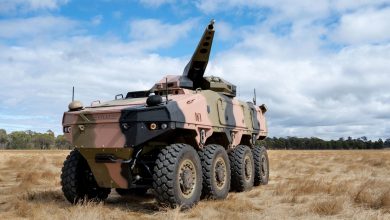 ATLAS UGV autonomous armored vehicle with an elevated cannon system, parked in an open field during testing.
