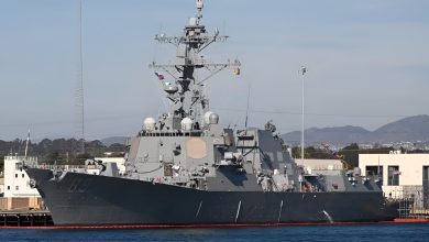 A modern U.S. Navy destroyer moored at port, showing its superstructure, sensors, and deck-mounted Mk 38 weapon system used for close-in surface defense.