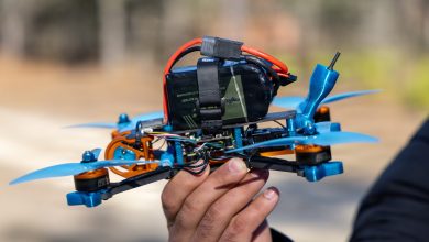 A U.S. Army Soldier assigned to 7th Special Forces Group (Airborne) holds a student-built FPV drone—complete with carbon fiber frame, blue propellers, orange anodized motors, strapped lithium-polymer battery, and exposed wiring—following successful assembly during the Operator Drone Basic Course at Eglin Air Force Base, Florida, Jan. 26, 2027. After Week 1 hands-on construction, troubleshooting, and simulator training, students walk away with a fully functional drone they built themselves, enabling Green Berets to deploy these unmanned systems for reconnaissance, precision observation, or action—placing robots in harm's way to protect personnel and enhance situational awareness on future battlefields. (U.S. Army photo by Sgt. Jacob Bradford)