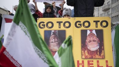 Iranian children stand behind an anti-US and anti-Israeli banner depicting portraits of US President Donald Trump and Israeli Prime Minister Benjamin Netanyahu in Tehran, Iran