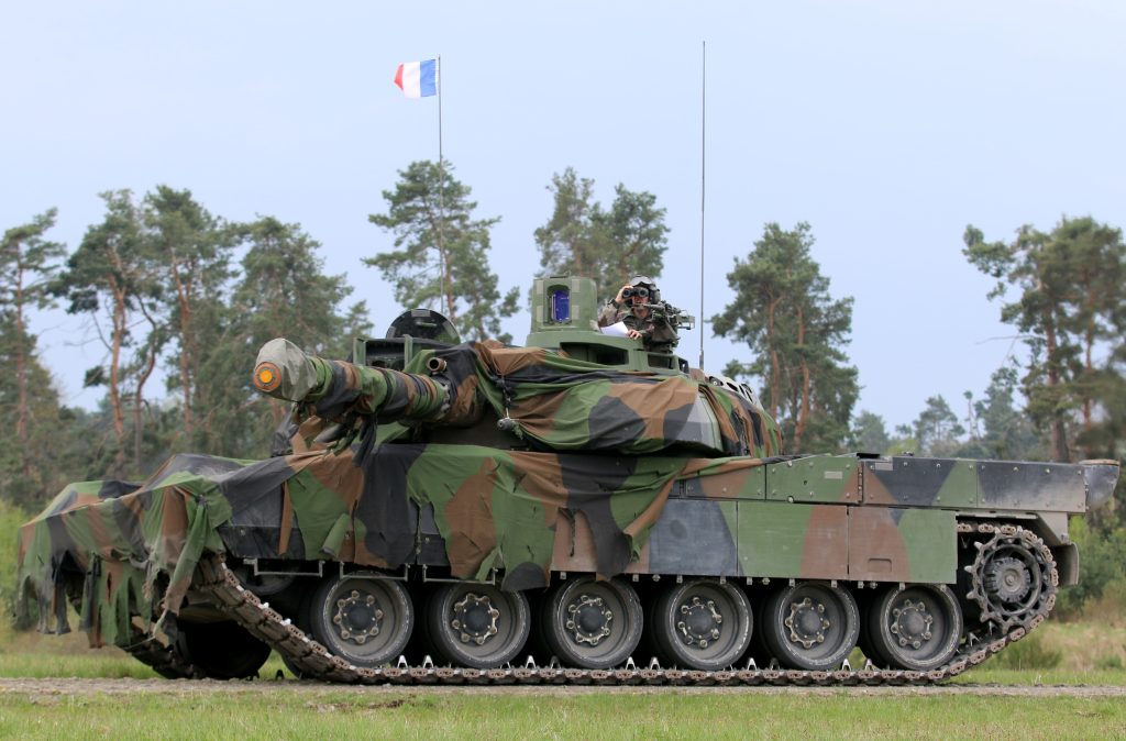 French Army Leclerc main battle tank draped in camouflage netting and flying the French tricolor during the Strong Europe Tank Challenge exercise, illustrating European armored warfare capability