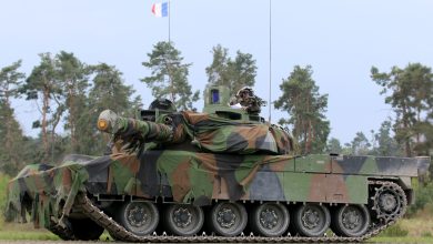 French Army Leclerc main battle tank draped in camouflage netting and flying the French tricolor during the Strong Europe Tank Challenge exercise, illustrating European armored warfare capability