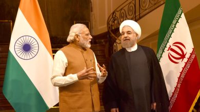 Narendra Modi shaking hands with Iranian President Hassan Rouhani with Indian and Iranian flags behind them.
