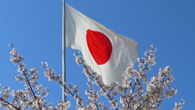 The Japanese national flag waves amidst blooming cherry blossoms under a clear sky in Hiroshima, Japan, on April 5, 2026.