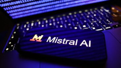 A binary code displayed on a laptop screen and Mistral AI logo displayed on a phone screen are seen in this illustration photo.