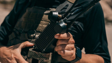 Soldier in tactical vest holding Neros Crossbow Block 2 wearable drone control station with multi-antenna array