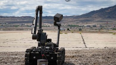U.S. Air Force Airman 1st Class Garrett Haynie, 366th Civil Engineer Squadron explosive ordinance disposal technician, operates a bomb defusal robot while a 366th Fighter Wing F-15E Strike Eagle flies overhead at Wendover Air Field, Utah, May 20, 2022 as part of exercise Raging Gunfighter 22-2. This exercise prepares the 366th Fighter Wing for Agile Combat Employment (ACE) operations around the world. (U.S. Air Force photo by Staff Sgt. Danielle Charmichael)