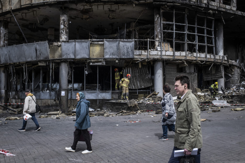 People are walking in front of a destroyed shopping mall in Liukanivka district in Kyiv.