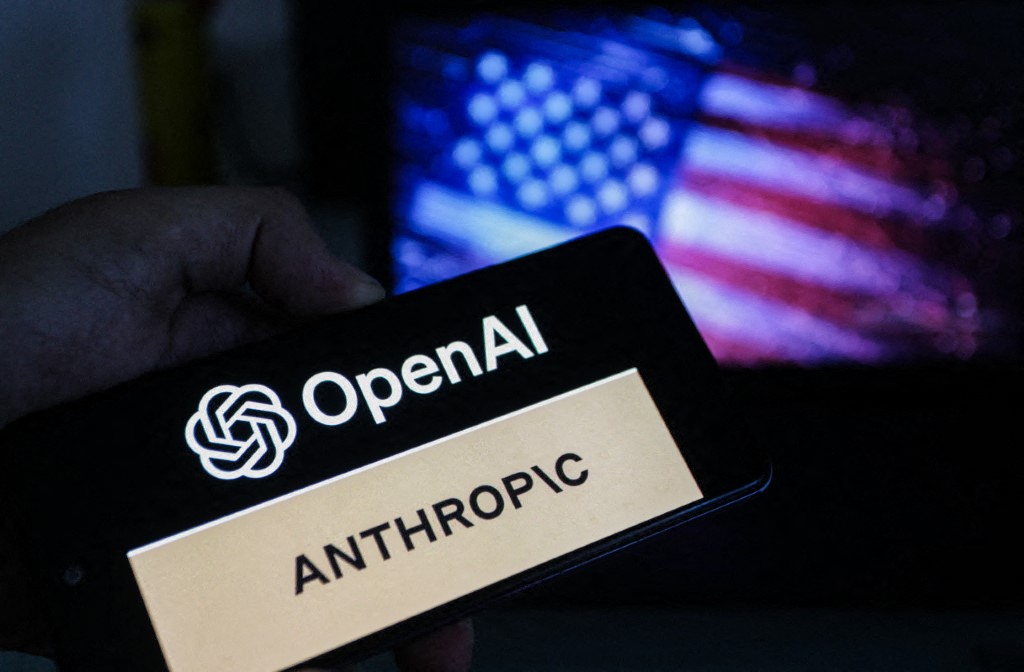 A smartphone displays the OpenAI and Anthropic logos in front of a blurred US flag. OpenAI has launched a US-only preview of its GPT-5.6 AI models following a federal national security review.