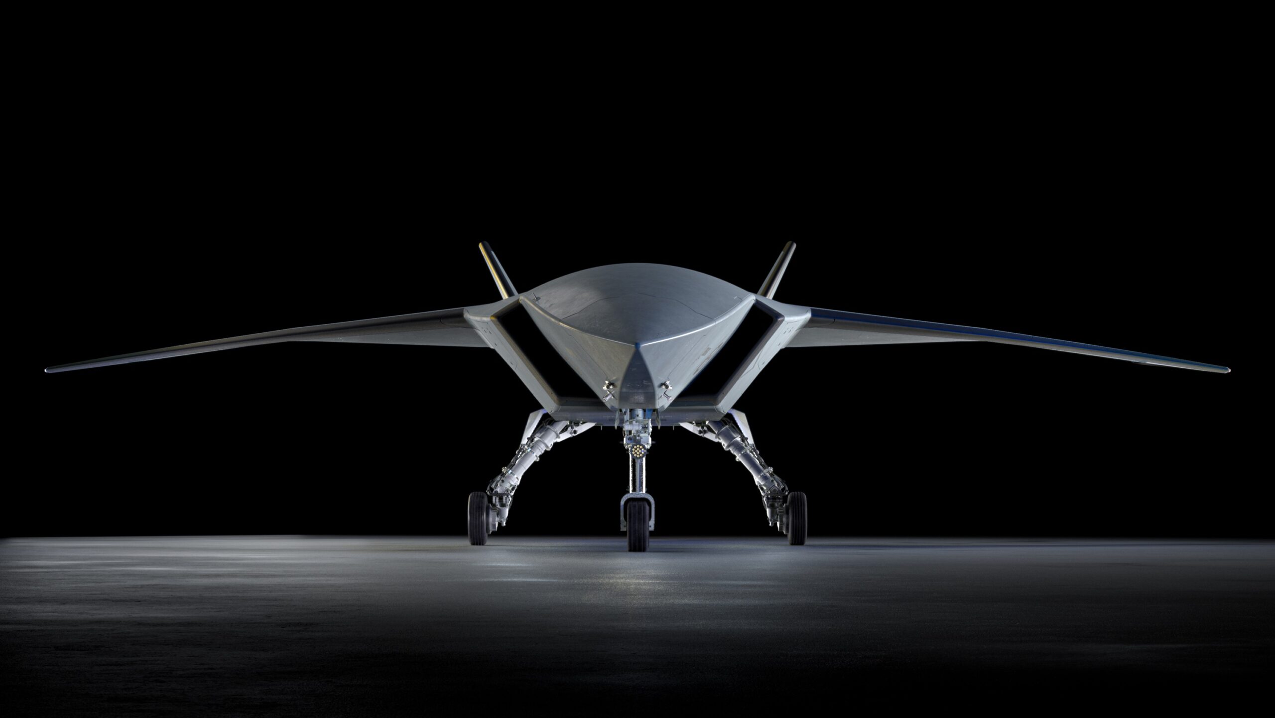Boeing MQ-28 Ghost Bat autonomous combat drone front view on hangar floor, showing low-observable flying wing design and tricycle landing gear