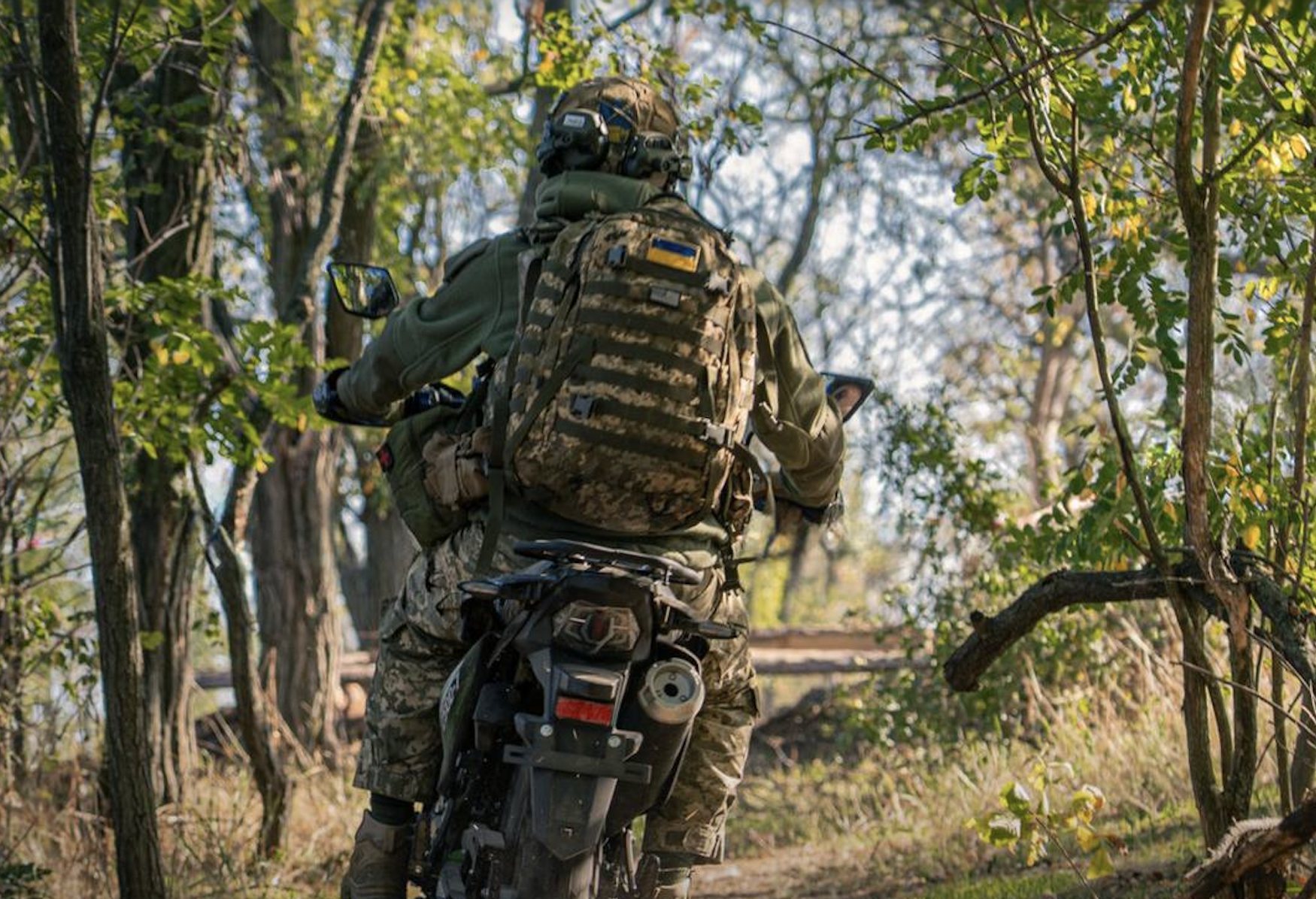 Ukraine soldiers ride a motorcycle.
