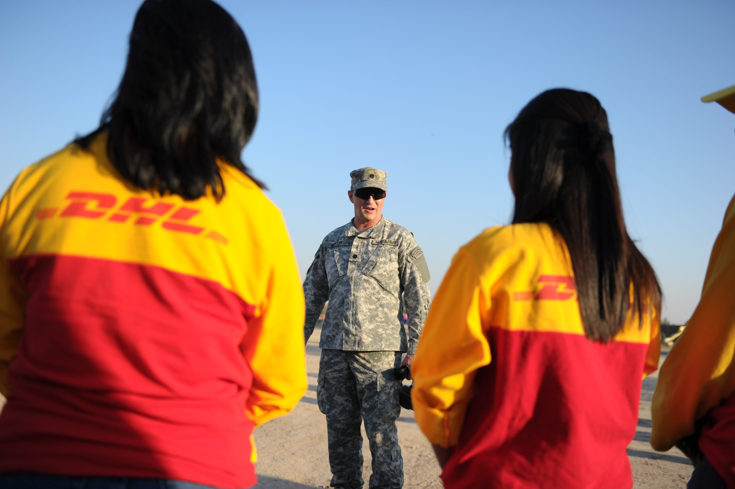 U.S. Army Lt. Col. John Motley, resource manager, assigned to United States Forces - Iraq, J33 Information Operations speaks with DHL workers in Victory Base, Baghdad, Iraq, Nov. 20. DHL workers delivered sporting goods to Kashafa, Iraqi Boy and Girl Scouts.