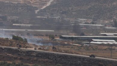 Israeli security forces drive on a road as smoke rises from fires in the area near the settlement of Itamar, in the north of the occupied West Bank.