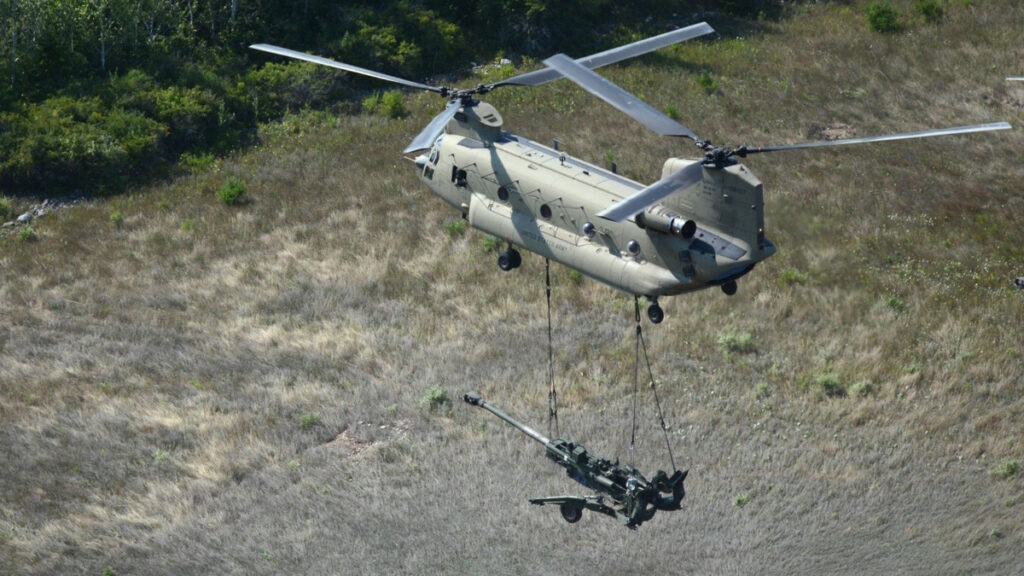 A CH-47F Block II carries a piece of artillery during training