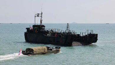 A Royal Navy LCU Mk10 landing craft and a vintage WWII DUKW amphibious vehicle flying the White Ensign flag during the D-Day 80th anniversary commemoration.