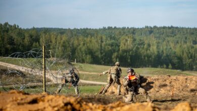 A US Army paratroopers assigned to 54th Brigade Engineer Battalion use a VS-17 panel to signal that the breach is clear for a maneuver element to move forward during a combined arms live fire exercise.