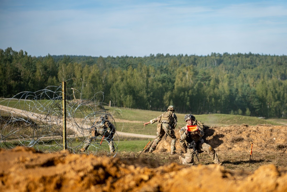 A US Army paratroopers assigned to 54th Brigade Engineer Battalion use a VS-17 panel to signal that the breach is clear for a maneuver element to move forward during a combined arms live fire exercise.