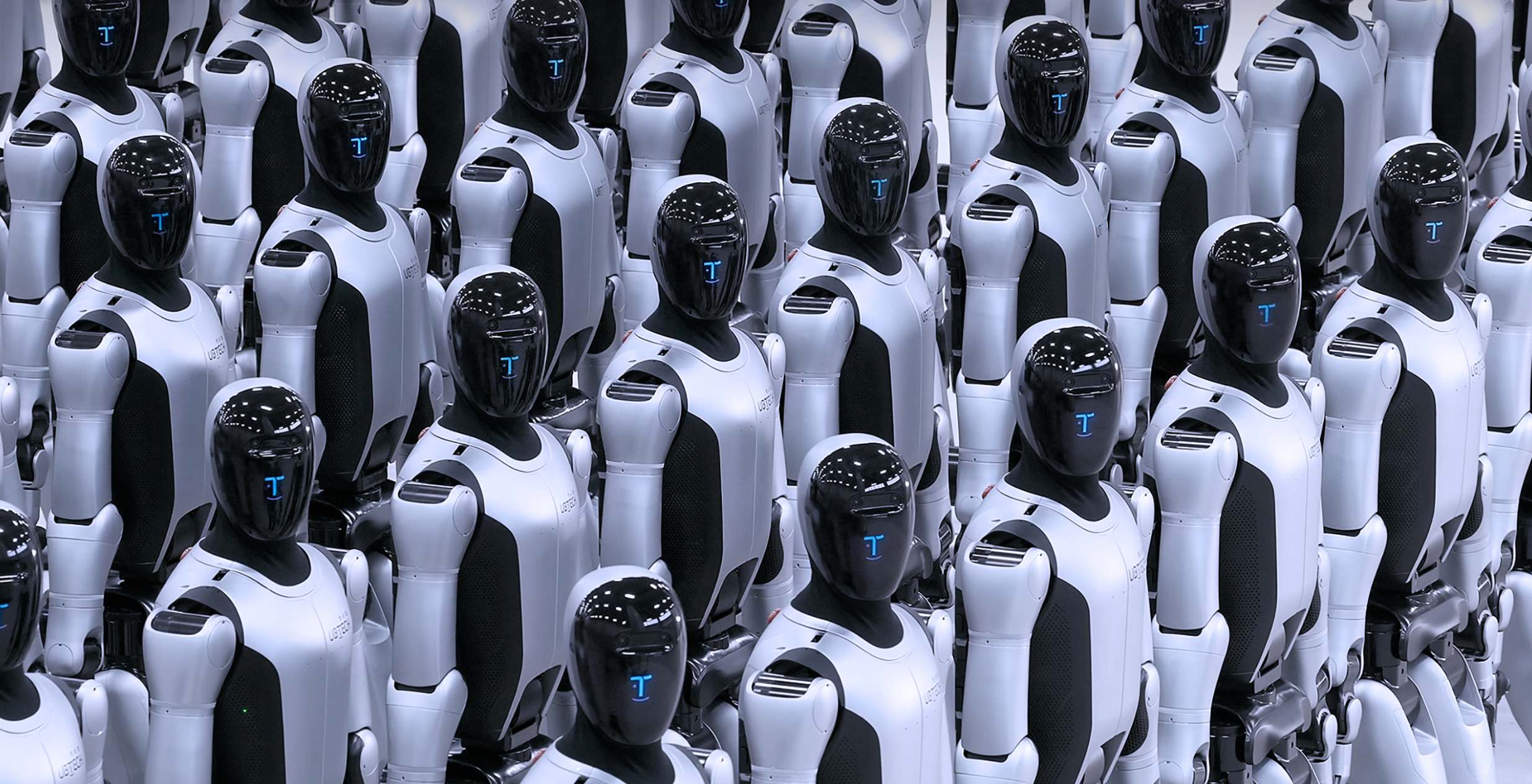 Rows of humanoid combat robots stand in formation, featuring white armored bodies and black visors with blue digital displays, resembling a mass-produced autonomous fleet
